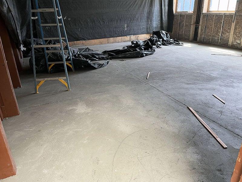 a smooth concrete floor with a wall that has studs and windows